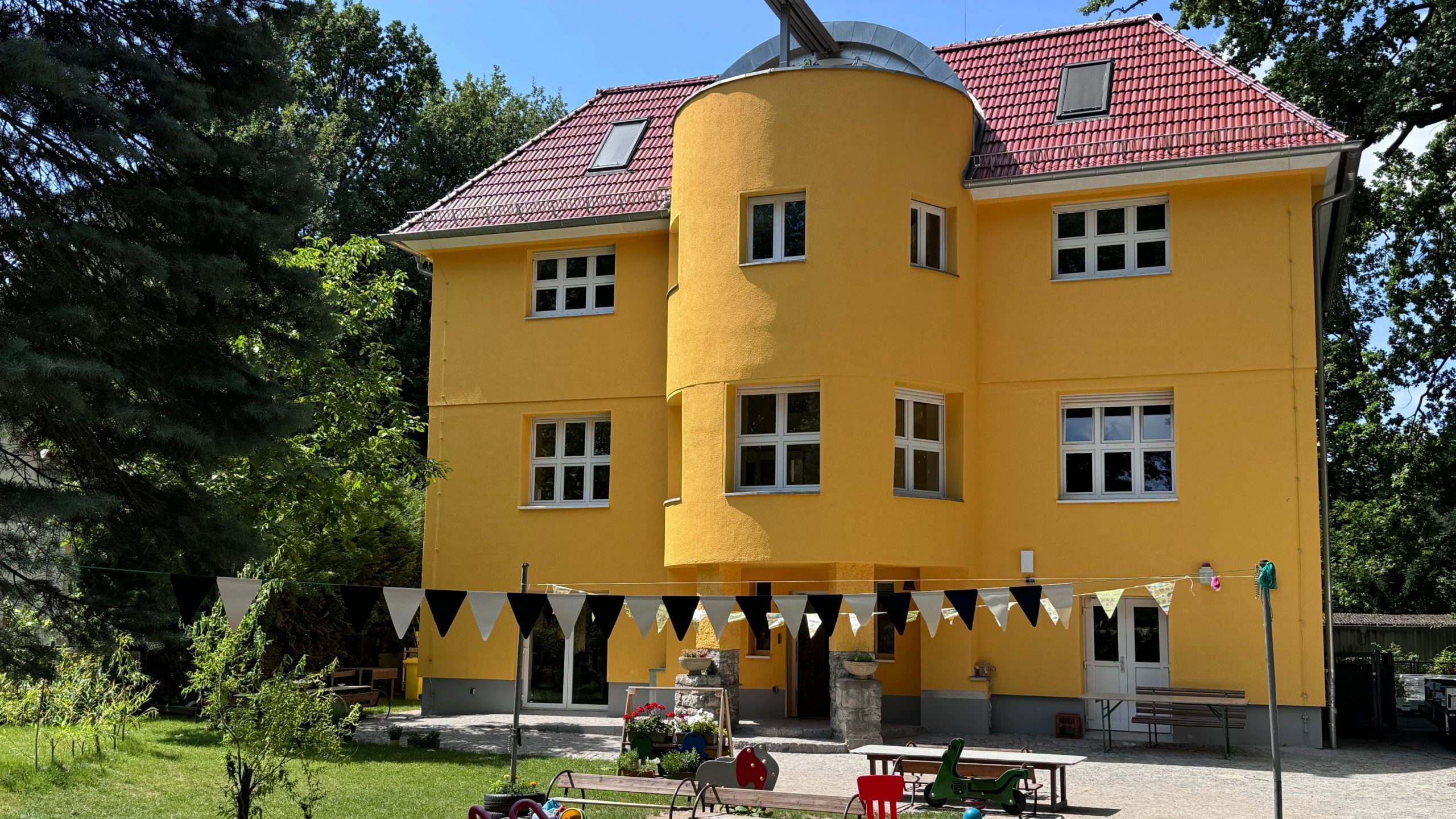 Frontalansicht der Kita Villa Bunterkunt mit gelber Fassade und rotem Dach nach Sanierung durch Niehof Bautechnik