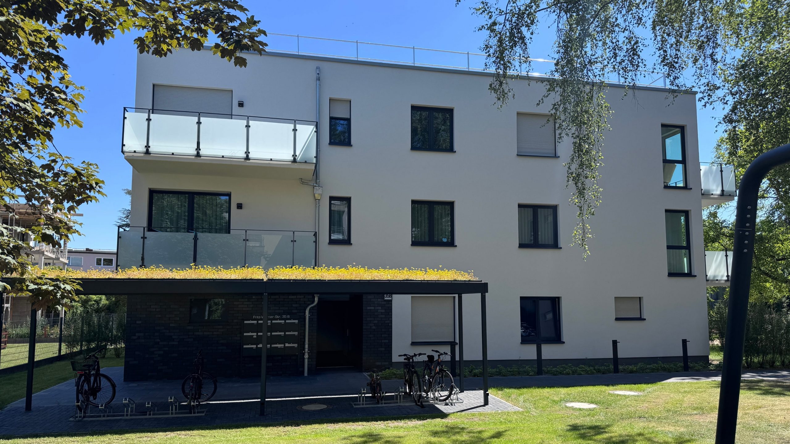 Modernes Mehrfamilienhaus mit begrüntem Vordach und Balkonen – fertiggestelltes Bauprojekt unter Betreuung von Niehof Bautechnik