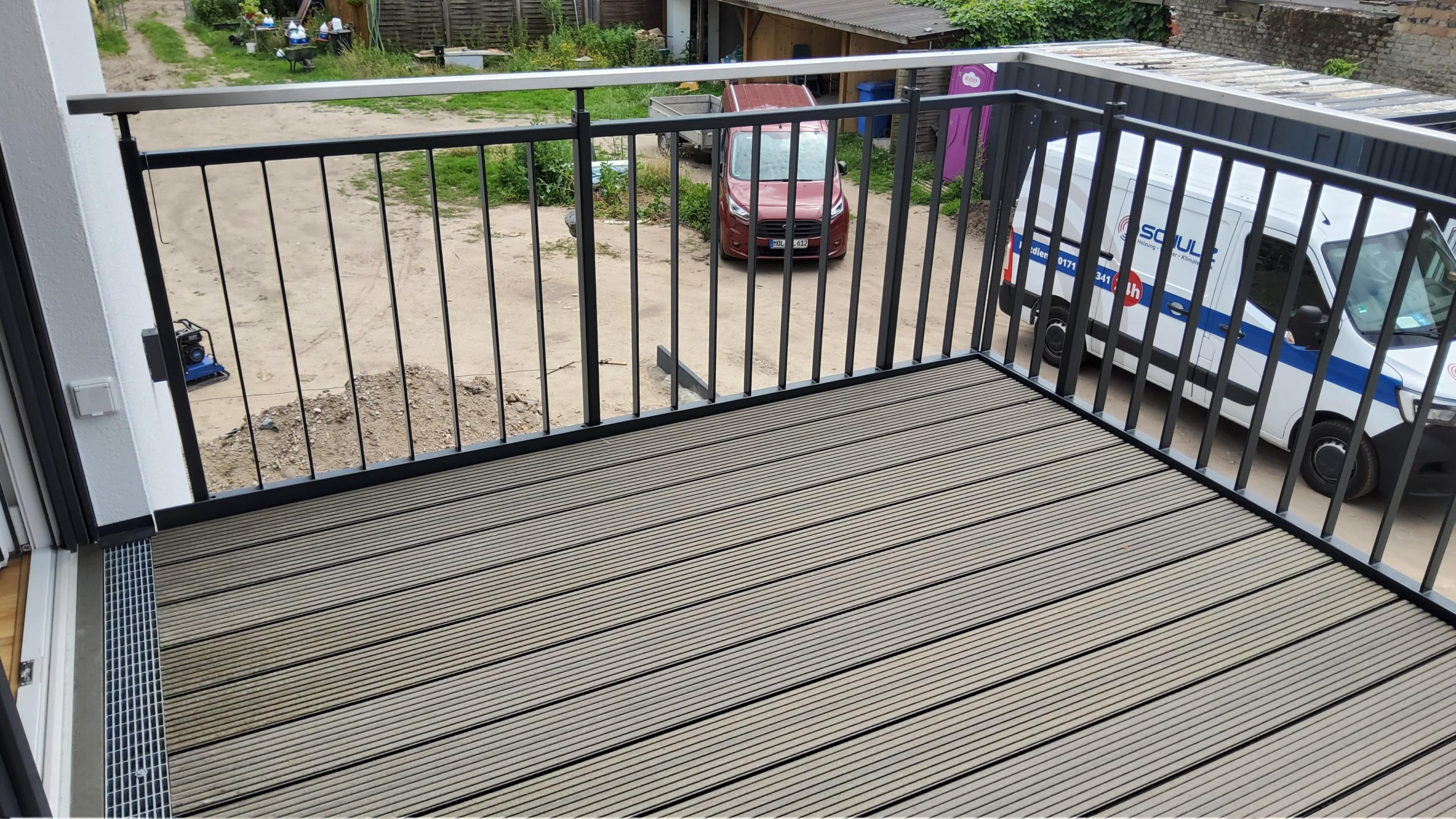 Balkon mit Holz- oder WPC-Dielenbelag und schwarzem Metallgeländer im Rahmen eines betreuten Bauprojekts