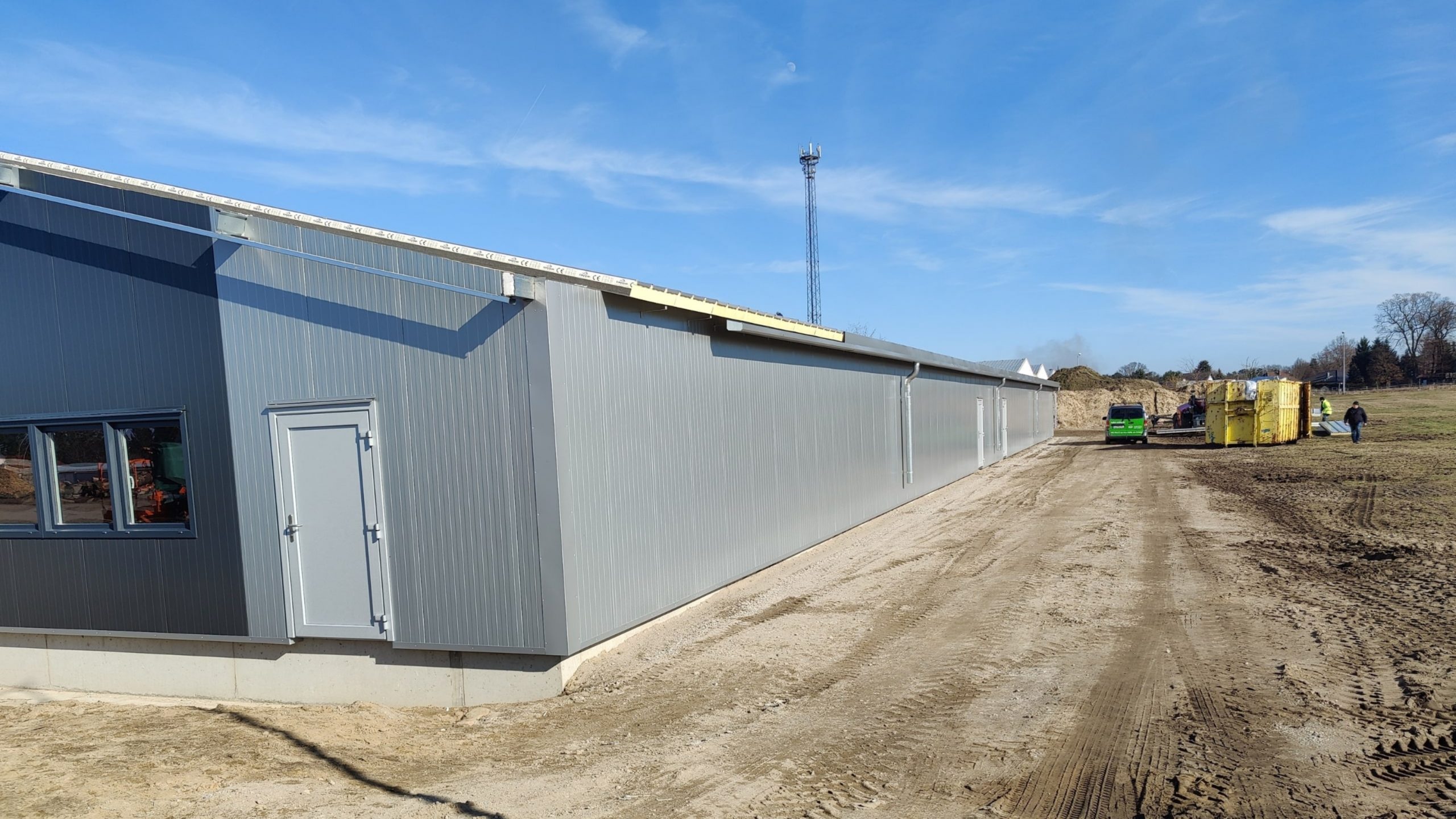 Nahezu fertiggestellte Lagerhalle mit Metallfassade, Fenstern und Baustellenbetrieb – betreutes Bauprojekt kurz vor Übergabe